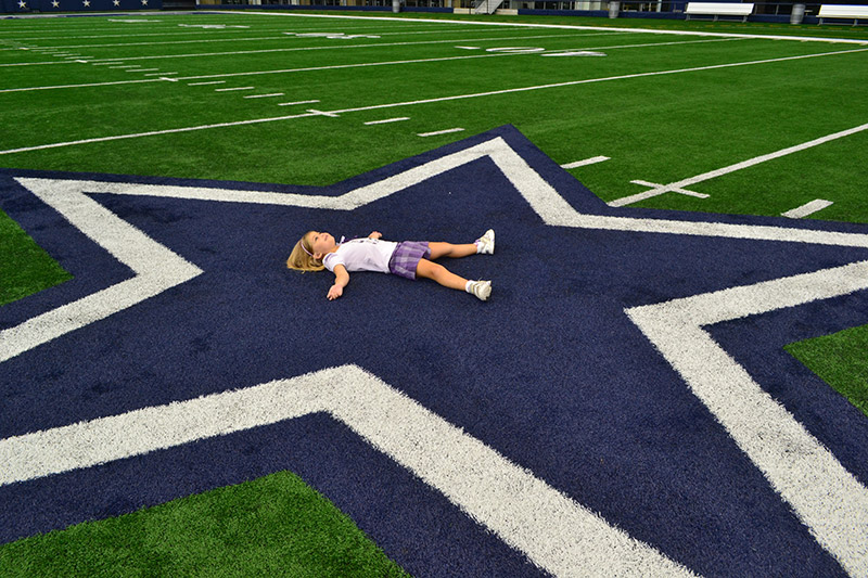 Dallas Cowboys Stadium: Alice deitada na estrela no campo